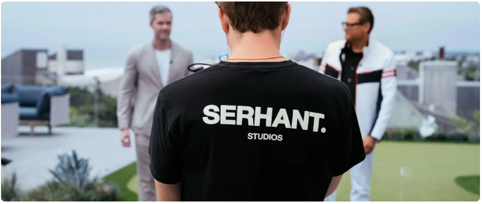 Back of serhant studios black tshirt two men talking out of focus waterfront